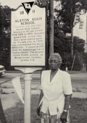 Photograph of Dr. Lela Session standing in front of the Alston High School historical marker, undated